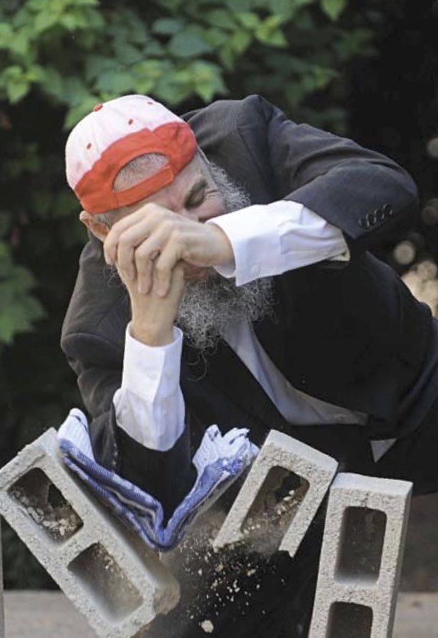Rabbi Fishel Jacobs breaking concrete blocks during a demonstration