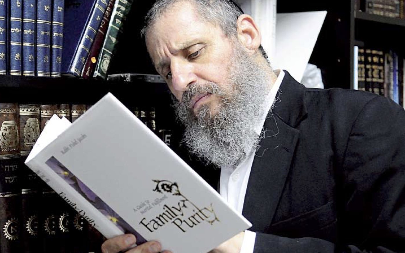 Rabbi Fishel Jacobs reading a copy of Family Purity